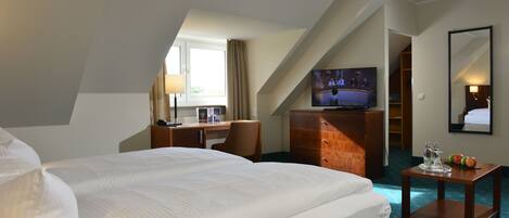 Una habitación de hotel con una cama grande, un escritorio con computadora, un televisor y un aparador.