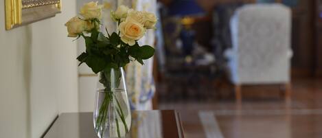 Un florero con flores sobre una mesa en una habitación con un espejo y una lámpara.