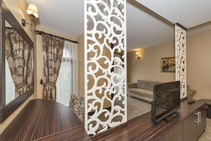 A modern living room with a dark wood TV stand, a beige sofa, and a decorative white partition.