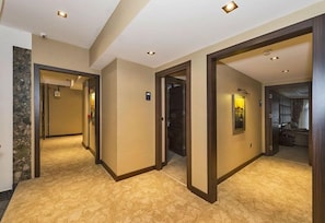 A hotel hallway with carpeted floors, wooden doors, and recessed lighting.