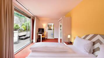 Ein Hotelzimmer mit Bett, Schreibtisch, Stuhl und Blick ins Freie.