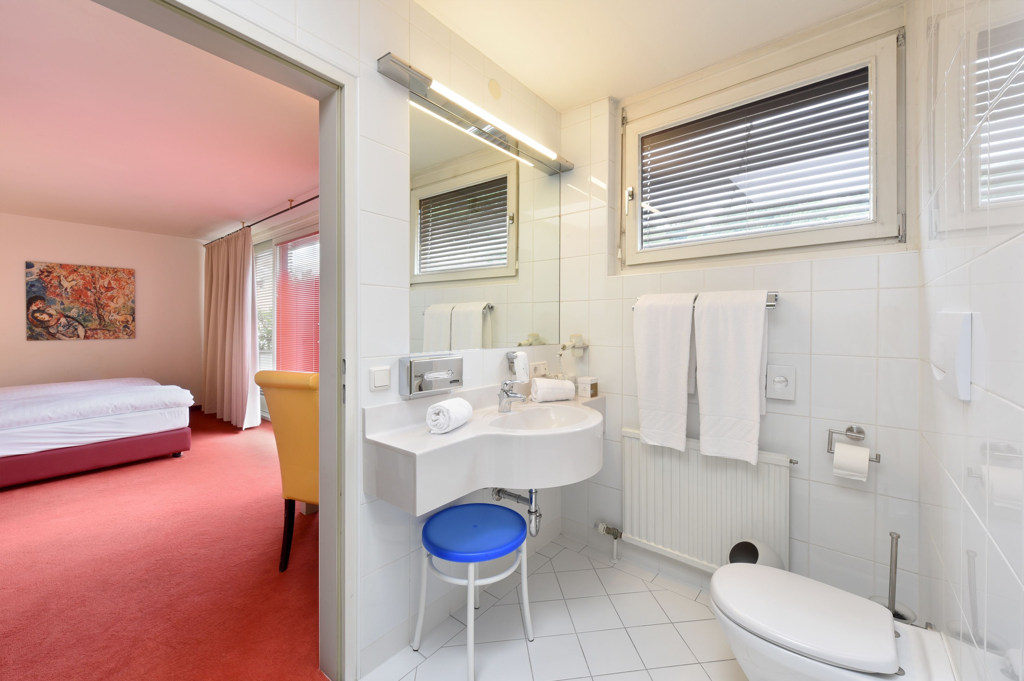 Ein Hotelzimmer mit Bett, Badezimmer mit Waschbecken, Toilette und Dusche.