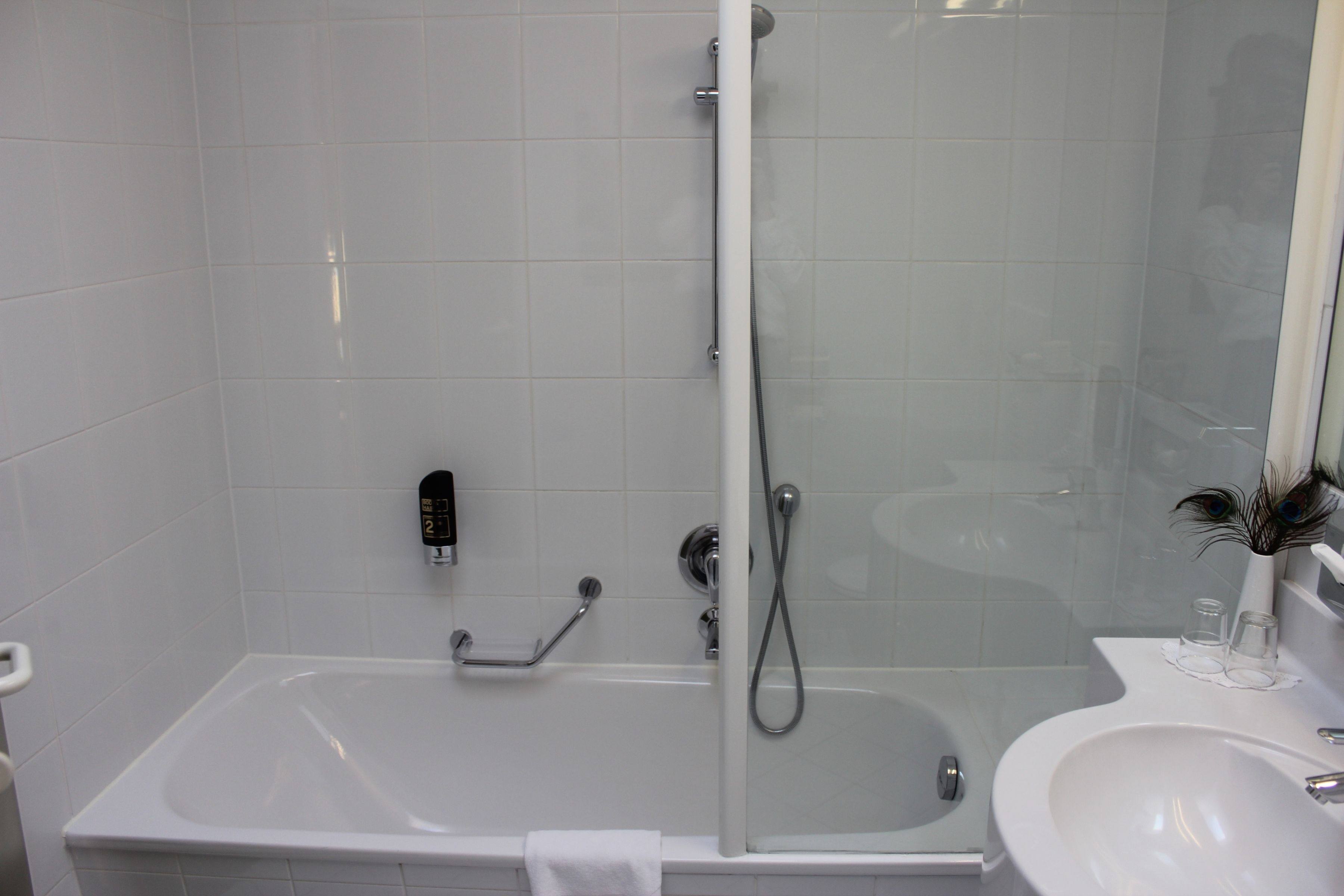 A modern bathroom with a glass-enclosed shower, a white bathtub, and a sink with a mirror above it.