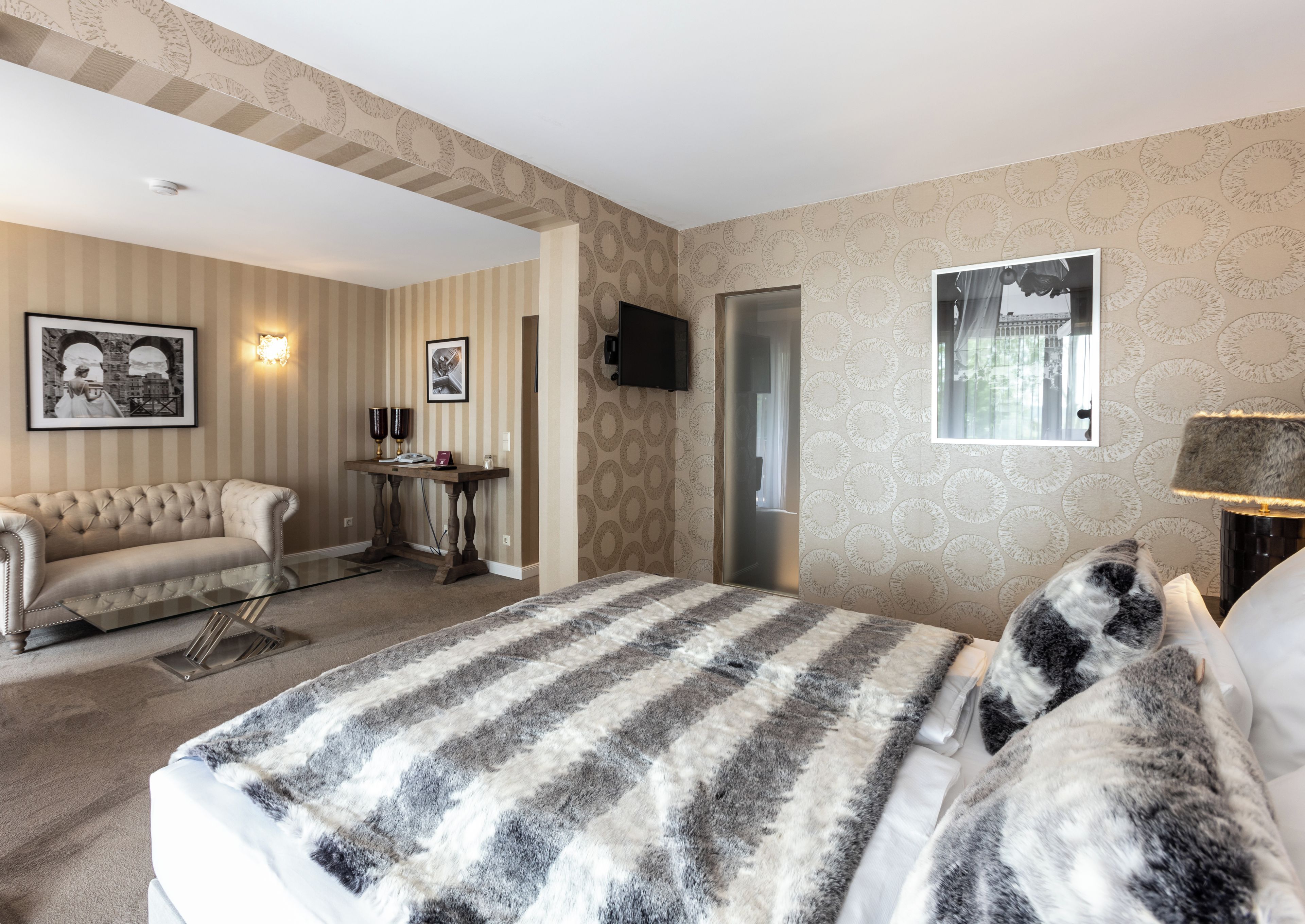 Una habitación de hotel con cama, sofá, una mesita y televisión.