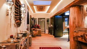 A hallway with a wooden floor, a glass table with decorative items, a red rug, and a skylight. - Waldhotel Luise (Freudenstadt)