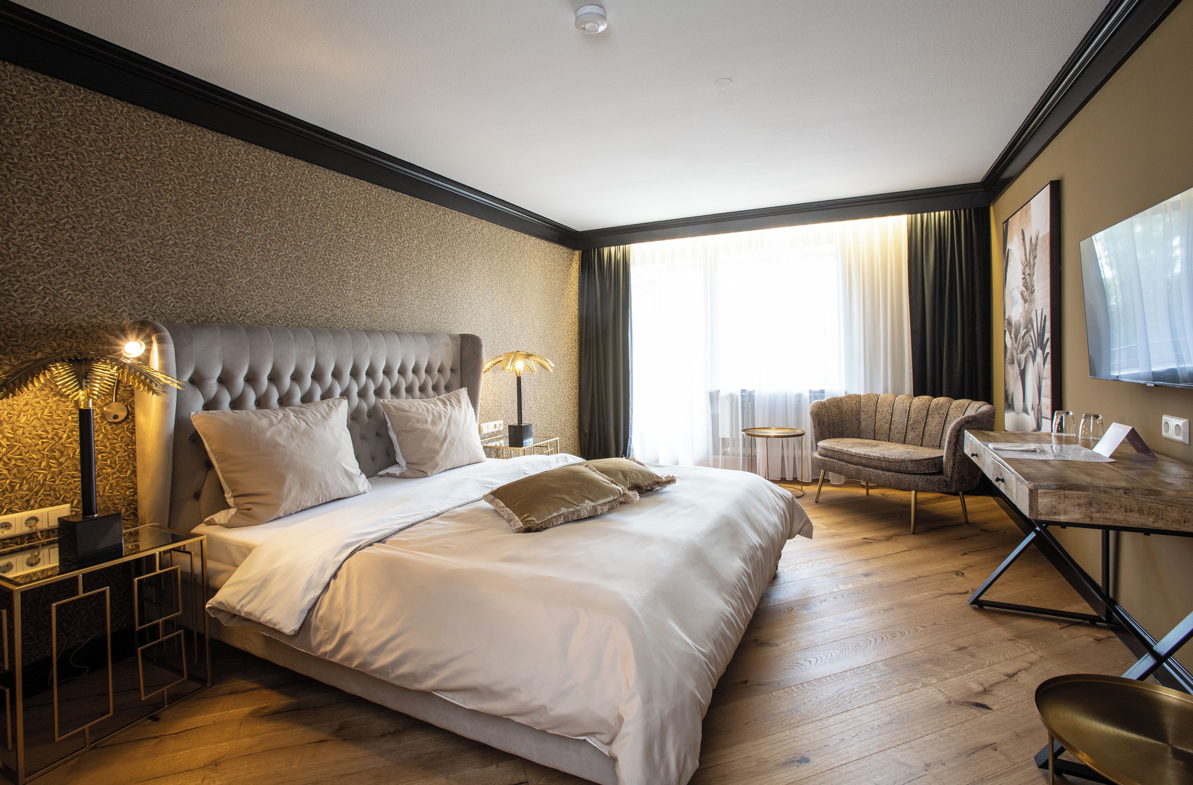 A hotel room with a large bed, a desk, a chair, and a television.