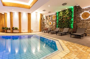 A swimming pool with lounge chairs and a stone wall with green plants.