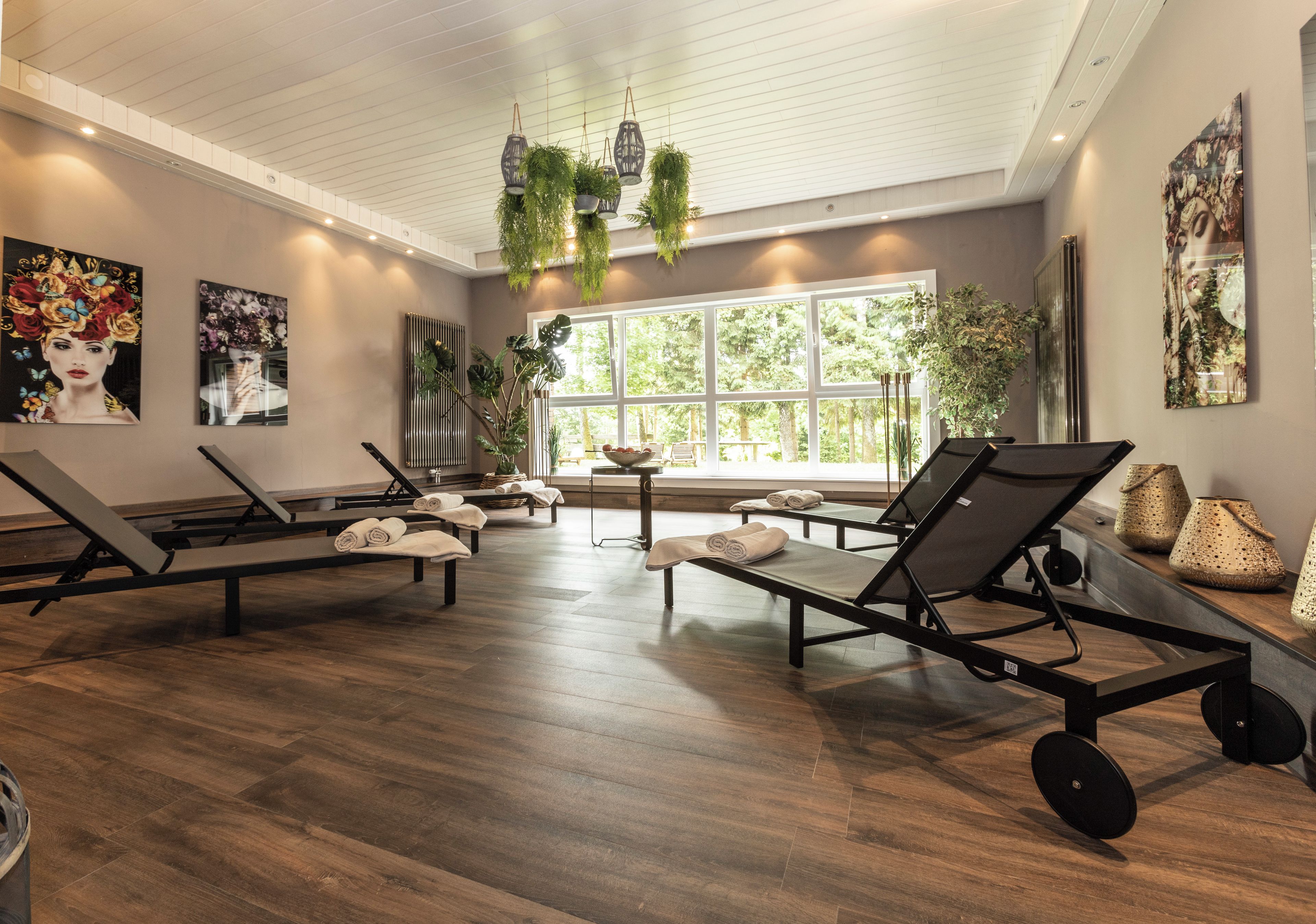 Un cuarto de spa con varias camillas de masaje, ventanas amplias y plantas de interior.