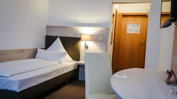 Ett hotellrum med en säng, ett skrivbord, en stol och en dörr.