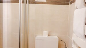 Une salle de bain équipée d’une douche, de toilettes et d’un porte-serviettes.