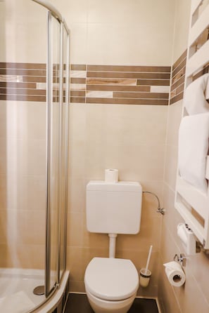 Un baño con ducha, inodoro y perchero para toallas.