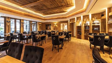 Un restaurante con techo y paredes de madera, varias mesas de comedor con sillas, y una zona de bar con estantes llenos de botellas.