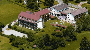 An aerial view of a hotel with multiple buildings, a parking lot, and surrounding greenery.