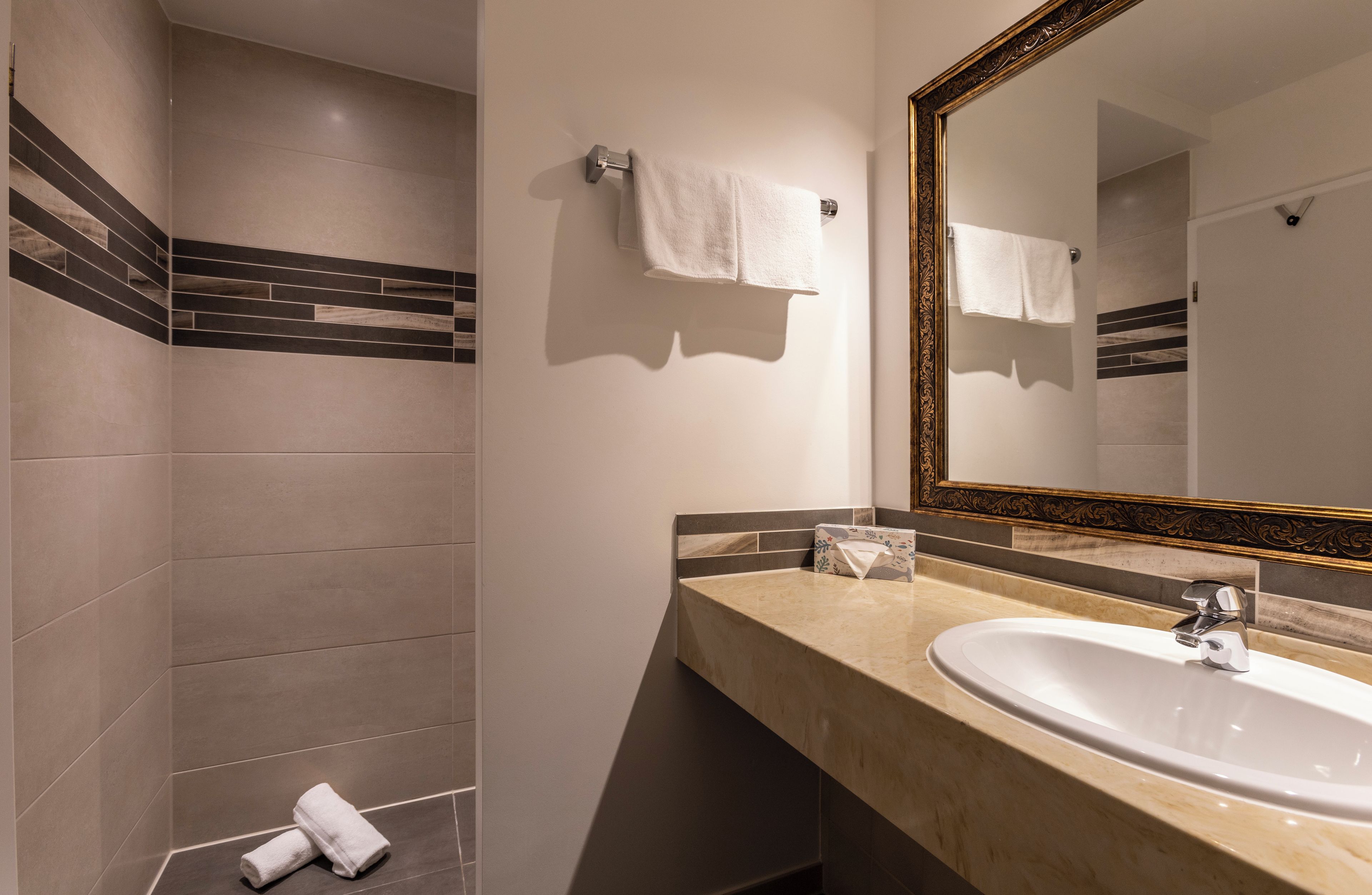 A modern bathroom with a large mirror, a sink, and a shower area.