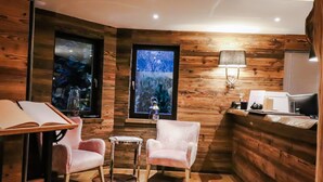 A cozy room with wooden walls, a comfortable chair, a small table, and a TV mounted on the wall. - Waldhotel Luise (Freudenstadt)