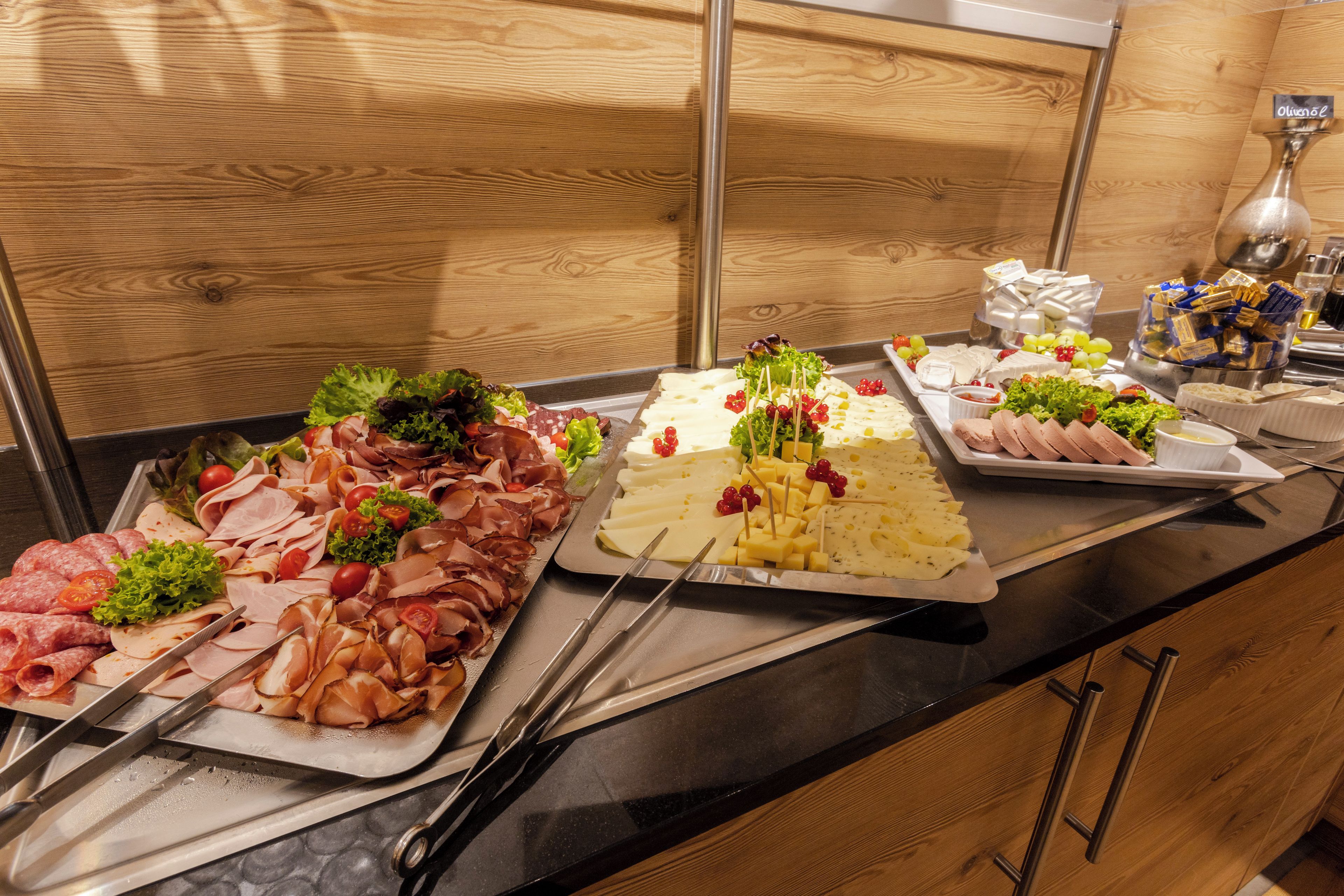 A buffet with various meats, cheeses, and fruits.