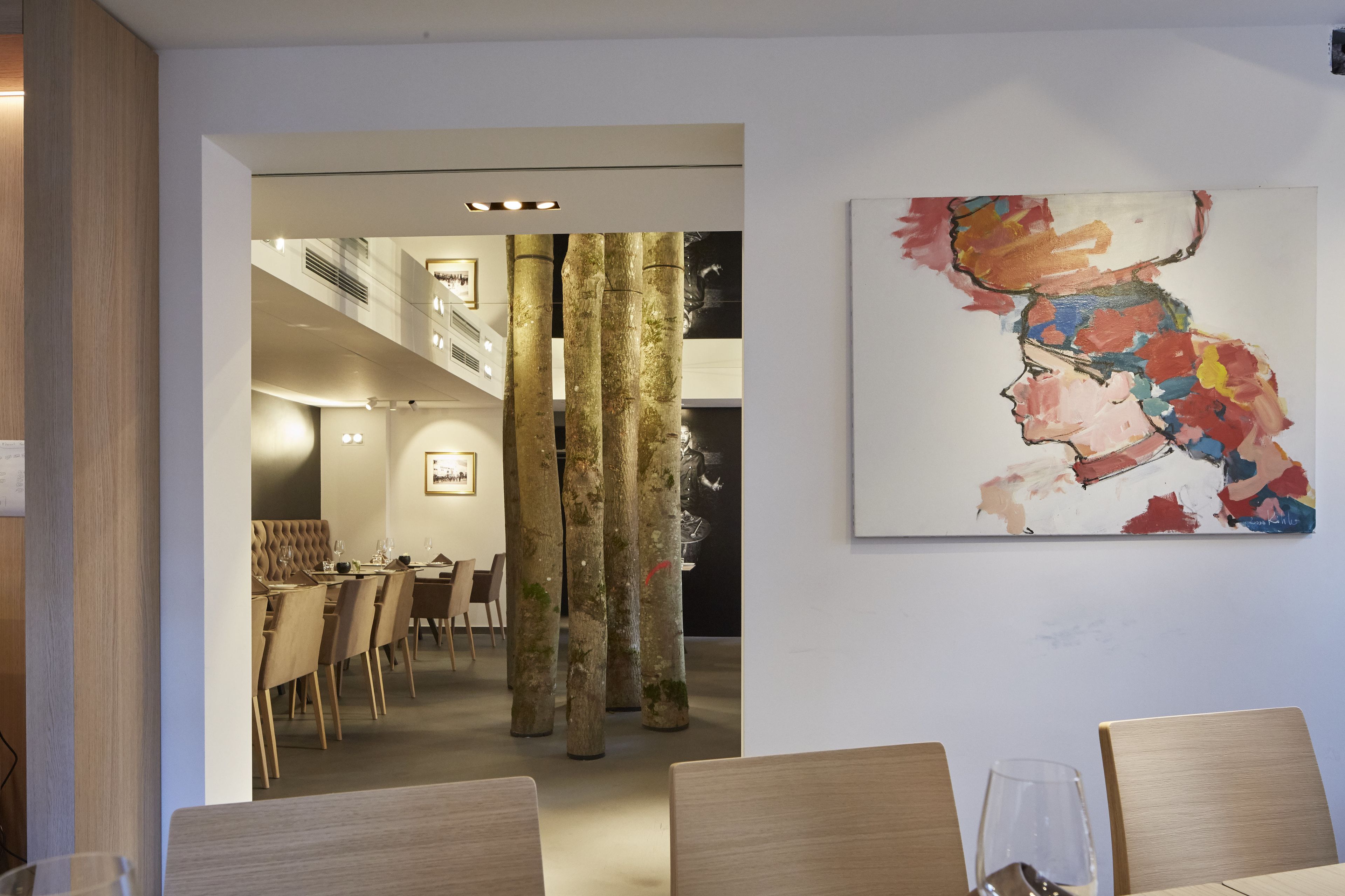 A modern dining area with wooden furniture and a large abstract painting on the wall.