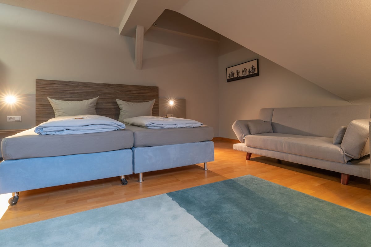 Un dormitorio moderno con cama, sofá y un amplio ventanal.