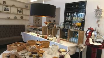 A buffet setup with various food items, a coffee machine, and a wine rack.