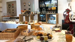 Ein reichhaltiges Buffet mit verschiedenen Speisen, darunter Gebäck und Beilagen, sowie einer Auswahl an Getränken.