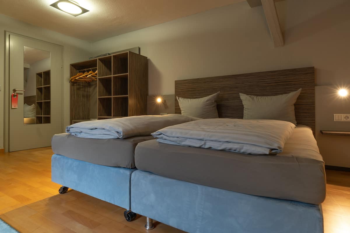 Una cama doble con cabecera, un armario de madera y un espejo en un dormitorio.