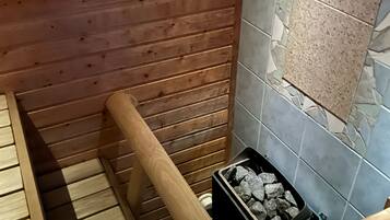 Interno di una baita di legno con un secchio di metallo, una panca in legno e una scatola di carbone.