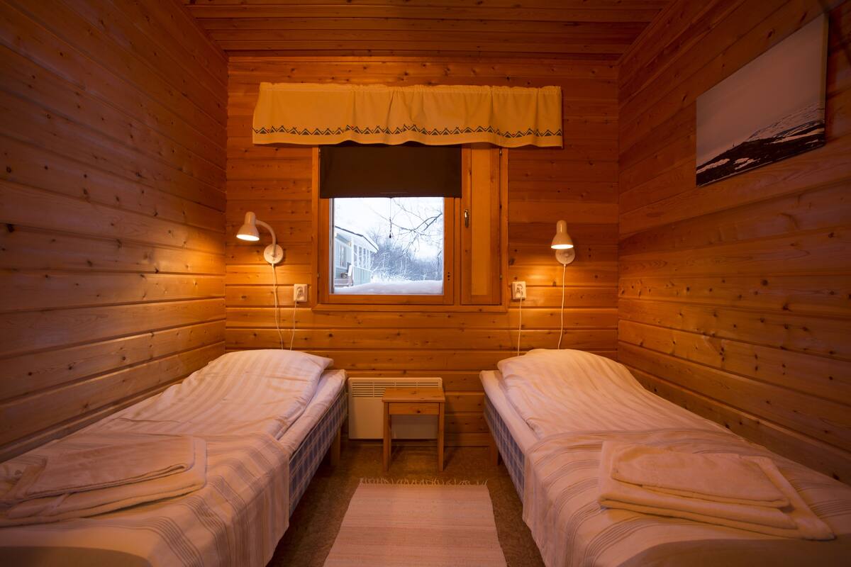 A cabin room with two beds, a window, and a small table.