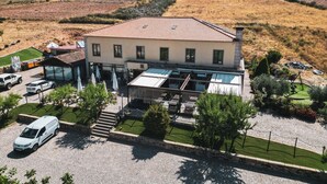 A two-story building with a tiled roof, a covered patio area, and a paved driveway. - Hotel Rural Senhora De Pereiras (Vimioso)