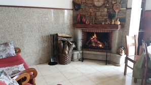 A cozy living room with a stone fireplace, a red sofa, and a wooden chair. - Hotel Rural Senhora De Pereiras (Vimioso)