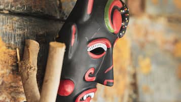 A wooden mask hanging on a rustic wall.