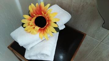 Een badkamer met een witte handdoek en een decoratieve zonnebloem op een zwarte dienblad.