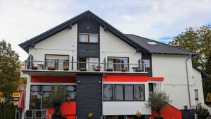Een modern, twee verdiepingen hoog gebouw met een balkon, een bord met restaurant en terras.