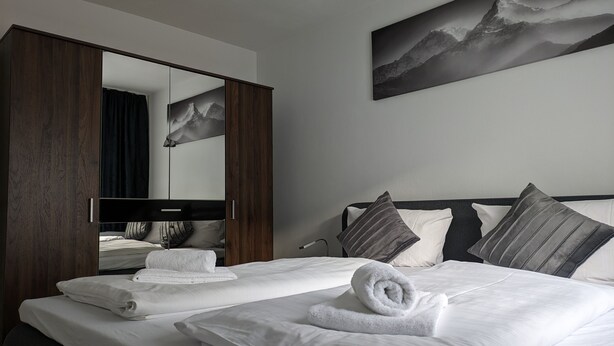 Een hotelkamer met een groot bed, een kledingkast, een spiegel en een schilderij aan de muur.