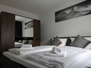 A hotel room with a large bed, a wardrobe, a mirror, and a painting on the wall. - Hotel Ari (Kaiserslautern)