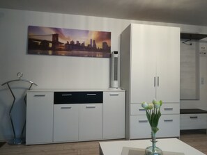 Eine moderne Küche mit weißen Schränken, einer Wand-Klimaanlage und einem Stadtbild.
