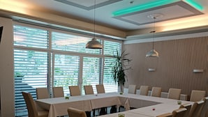 Een vergaderruimte met een grote tafel, meerdere stoelen en een kamerplant.