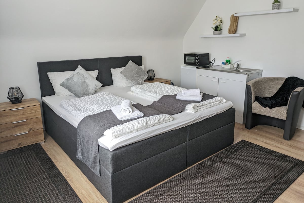 Une chambre moderne avec un grand lit, des tables de chevet, un petit bureau, une chaise et un four à micro-ondes.