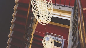 Een trap met een unieke, geometrische lamp die aan het plafond hangt.