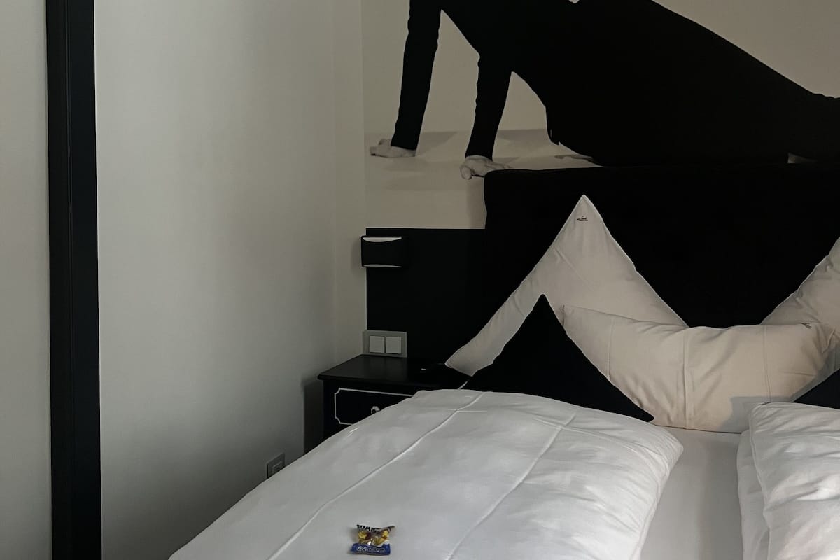 Een slaapkamer met een bed, een nachtkastje en een wandplank.