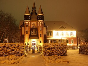 A castle-like building with a central tower, a large entrance, and a well-lit facade.