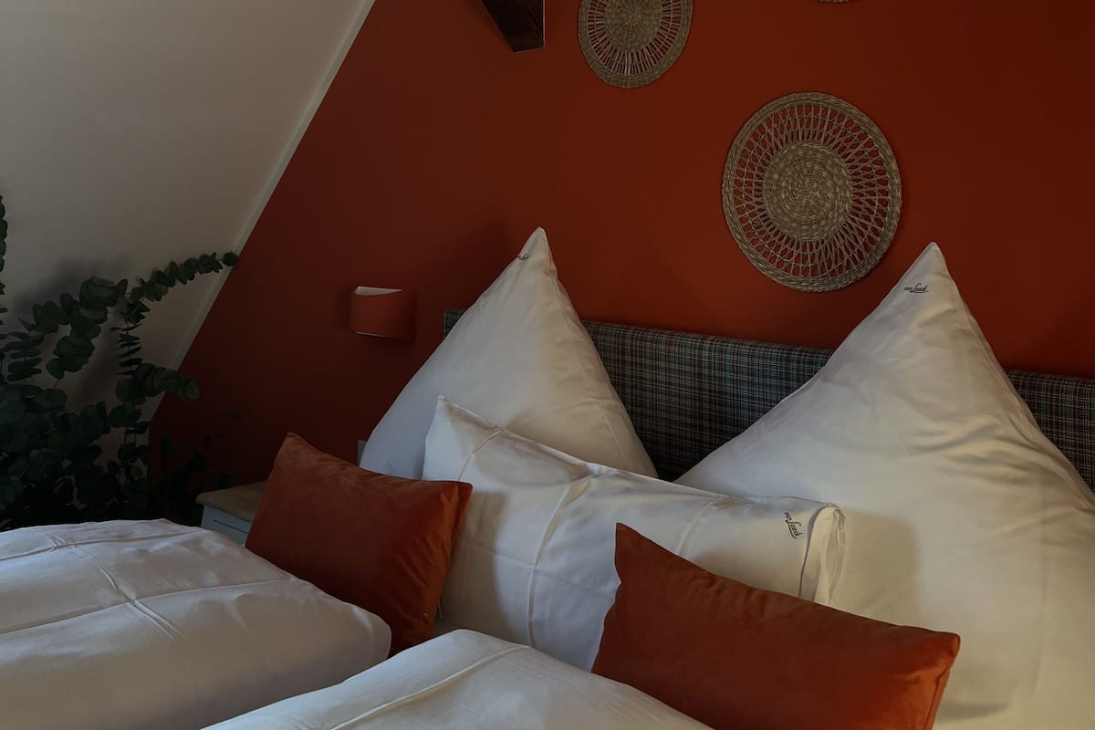 Een slaapkamer met een bed, kussens, een wandlamp en decoratieve wandversieringen.