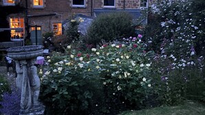 A stone building with multiple windows and a well-maintained garden with various flowers. - Ellesmere House (Castle Cary)