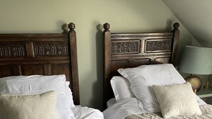 Two double beds with wooden headboards, white linens, and beige knitted blankets. - Ellesmere House (Castle Cary)