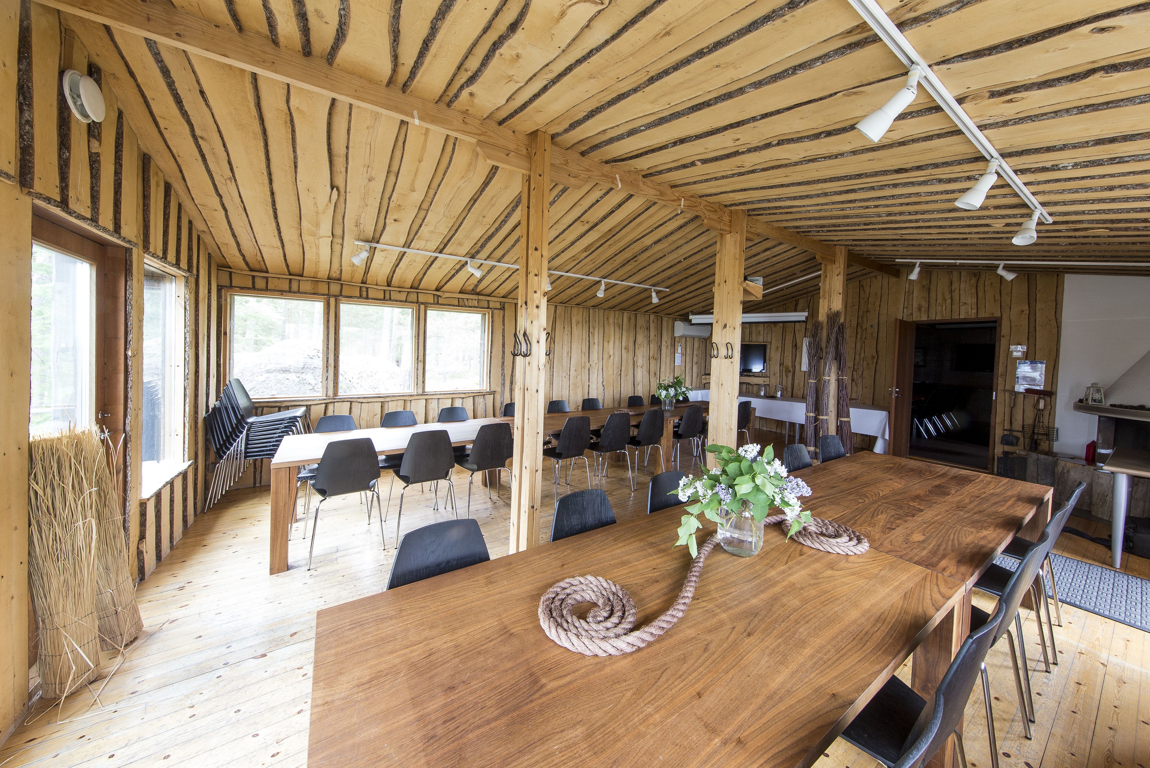 A wooden interior with a long dining table, chairs, and a ceiling with exposed beams.