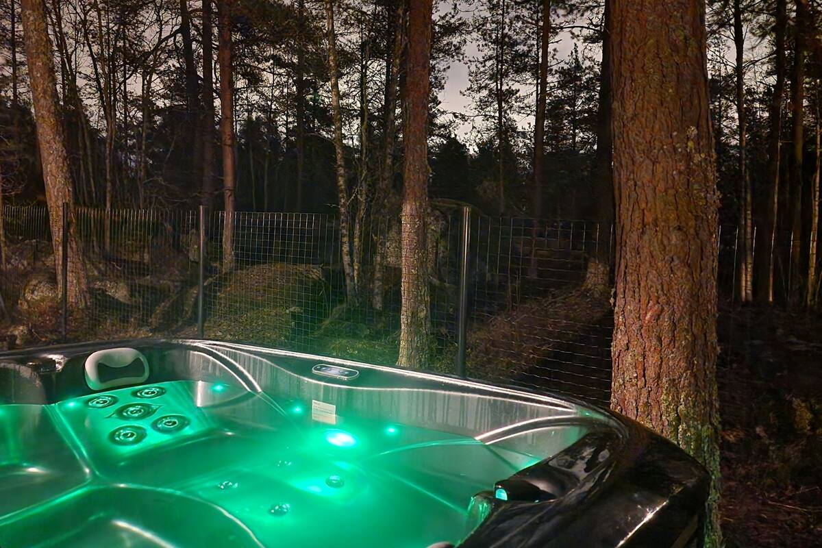 Uma banheira de hidromassagem com estrutura de vidro em meio à floresta.