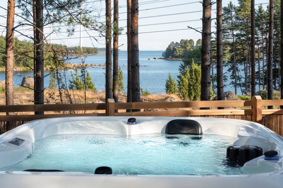 Uma banheira de hidromassagem com vista desimpedida para um lago e árvores ao redor.