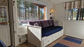 A cozy room with a built-in bed, a window with a view of trees, a lamp, and a radiator.
