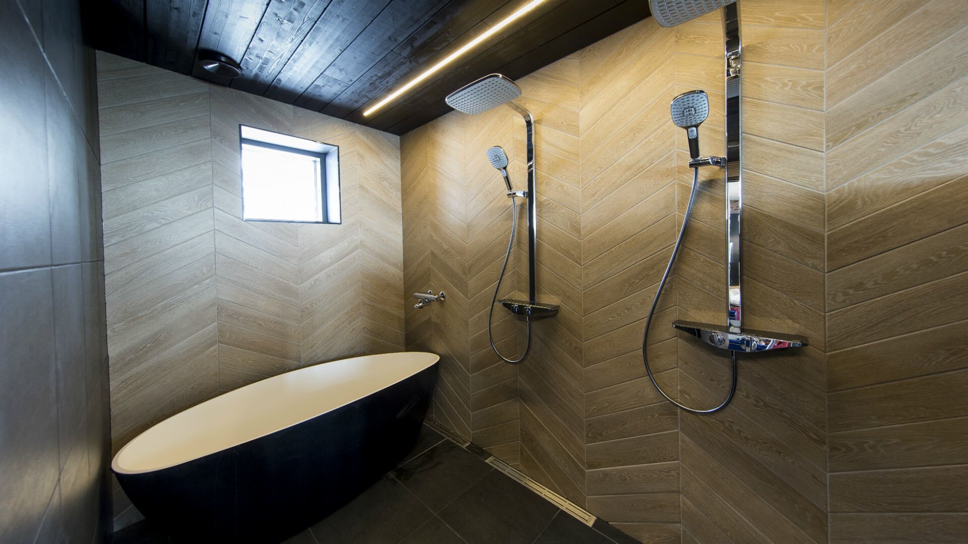 A modern bathroom with a freestanding bathtub, a shower with a handheld showerhead, and a wall-mounted showerhead.