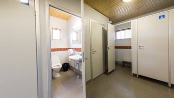 Des toilettes publiques comprenant des toilettes, un lavabo et une poubelle.