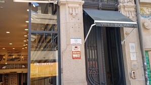 A storefront with a glass door, a sign for 'PRMETEUS' and 'Instalagens Protegidas', and a decorative metal gate. - Villa Bolhão Apartamentos (Porto)